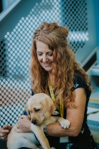 Jane Bradley smiling down at a golden labrador pup in her arms